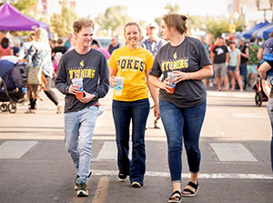 students walking down a street full of people and vendors