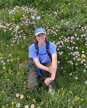 woman sitting in a mountain meadow full of wildflowers