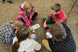 children in a group on the floor using a ball-shaped device