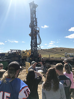 group of people looking at a drilling rig