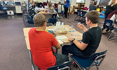 children in a classroom performing experiments at their desks