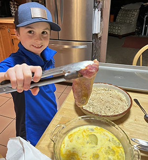 child using tongs to hold up food being prepared