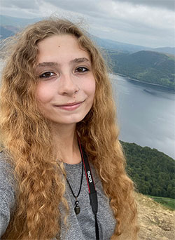 woman outside with water and mountains in the background