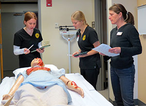 three people around a practice mannequin