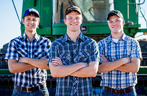 three men standing in front of a large tractor