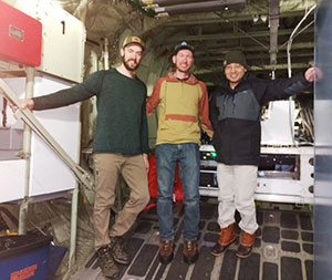 three people standing inside a plane