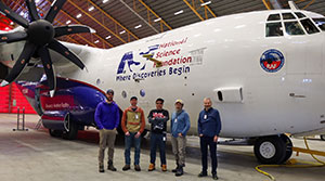 five people standing in front of a plane