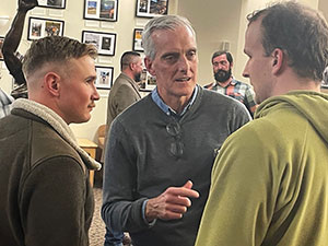 man talking to two other men