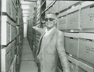 man gesturing to rows of boxes on shelves