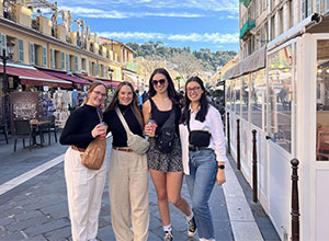 four people posing in a narrow European street