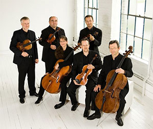 six people posing with string instruments