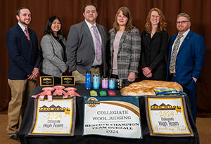 group of people posing behind a table filled with awards