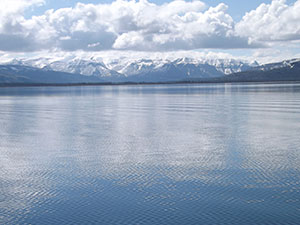 calm lake with snow-covered mountains and clouds in the background