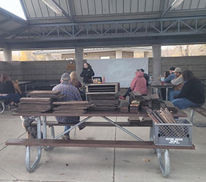 group of people listening to a speaker in an outdoor shelter