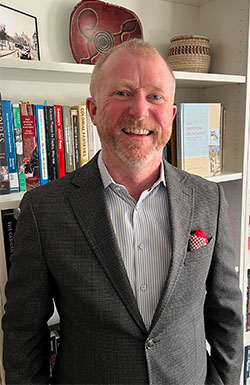 man standing in front of a bookshelf