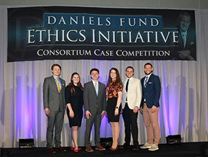 group of people posing on a stage under a banner