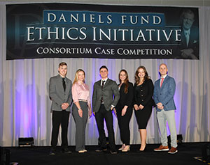 group of people posing on a stage under a banner