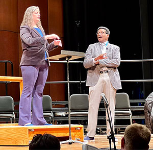 woman conducting with man looking on