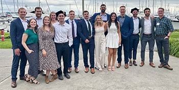 group of people posing outside by a marina
