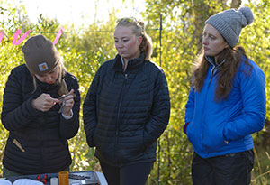 two people watching a third person measure a bird's wing