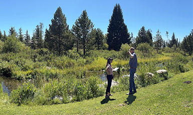 two people in a field beside a river