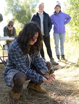 person crouching on the ground with a bird in hands