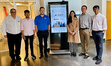 six people posing around a sign