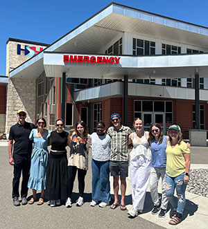 group posing in front of a hospital emergency entrance
