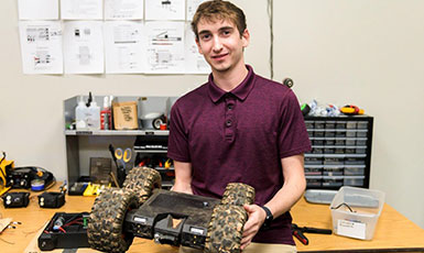 man holding a four-wheeled robot