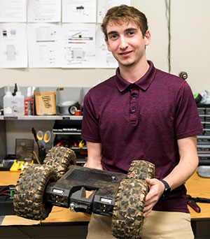 man holding a four-wheeled robot