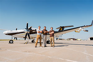 three people posing in front of the aircraft