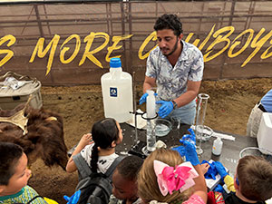man at a table performing a science experiment for watching children