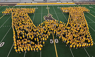 people in yellow shirts forming the letter w on a football field