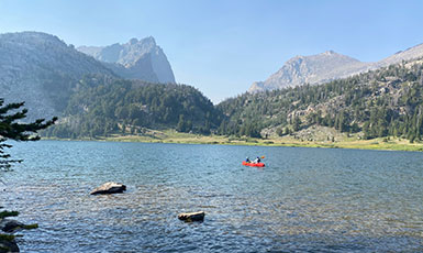 mountain lake with a small red boat on it