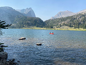 a mountain lake with a small red boat on it