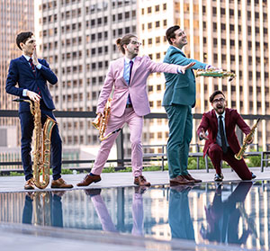 four people with saxophones on a wet city rooftop