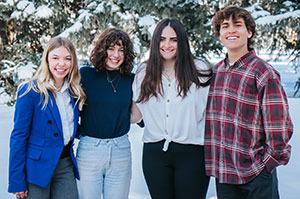 four people posing together in the snow