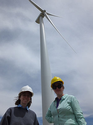 two people standing in front of a wind turbine
