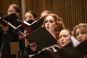 people holding music binders and singing