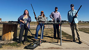 four people posing with hunting rifles