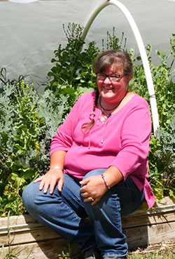 woman sitting on the edge of a raised bed garden
