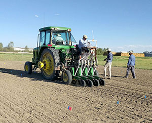 people working around and on a large tractor seeding a field