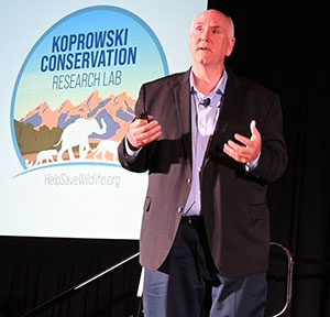 man speaking in front of a projected logo