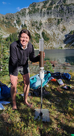 person with equipment beside a mountain lake