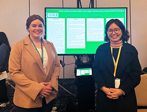 Two people standing in front of a display screen
