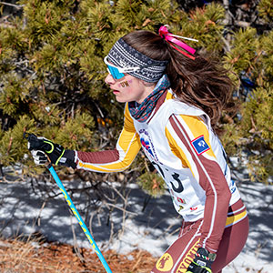 woman Nordic skiing with evergreens in the background