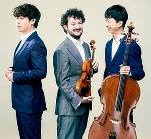 three people, two of them holding string instruments
