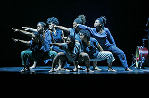 group of women all dressed in blue dancing on a darkened stage