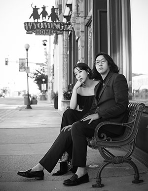 black and white photo of two people sitting on benches outside a business