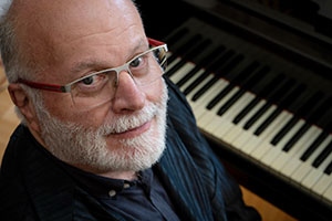 man sitting at a piano, looking up at the camera